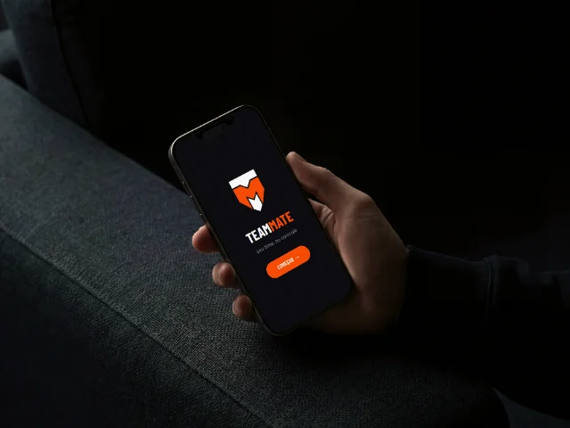 Mockup do app TeamMate em um iPhone, com logotipo em escudo laranja e tagline 'seu time, no controle'